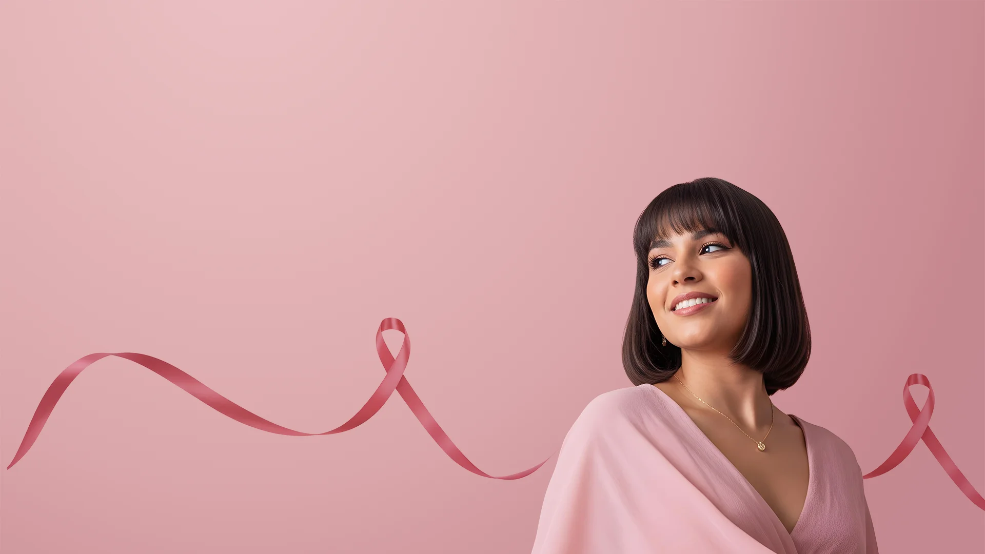 Mulher branca de cabelo curto de cor preta e camisa rosa, no fundo da foto um tom de rosa também e uma fitinha rosa em tom pink.
