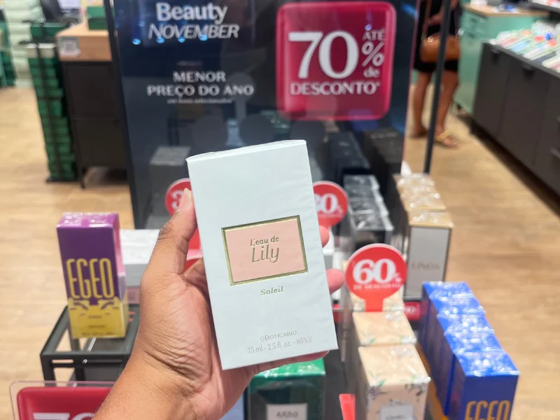 Mão masculina segurando embalagem de perfume L’eau de lily, que está na promoção de R$289,90 por R$164,90 (70%).